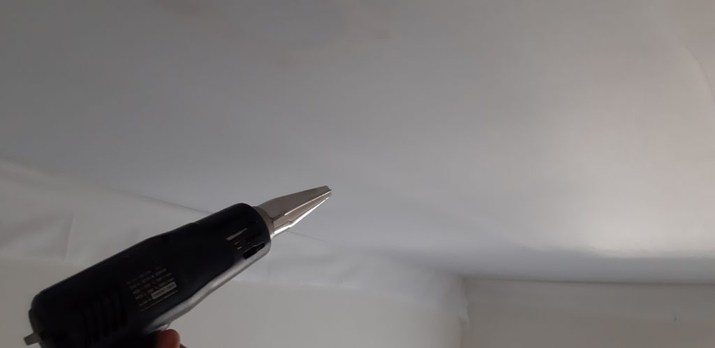 Removing wrinkles on a stretch ceiling with a construction hairdryer